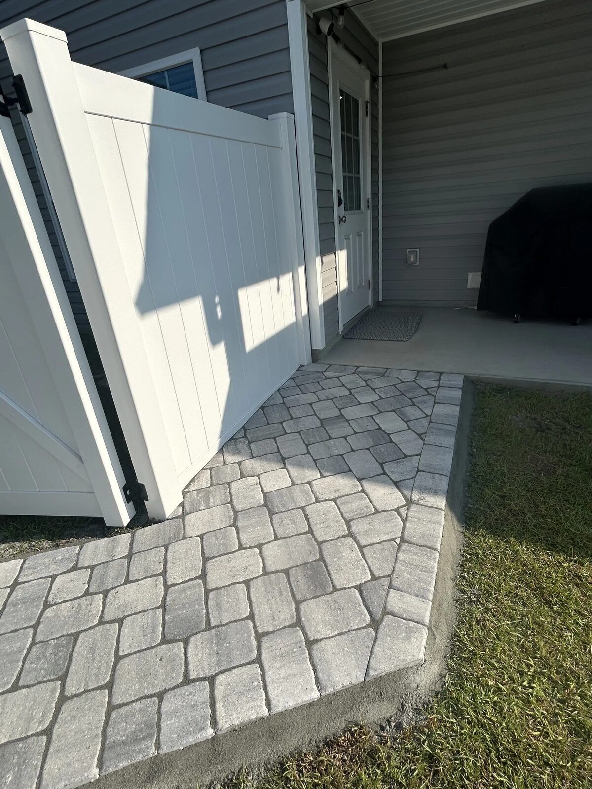 Paver walkway leading to a backyard patio
